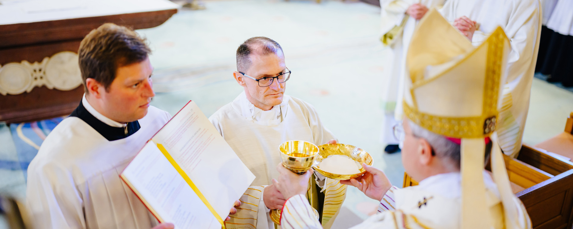 Brot in einer Hostienschale und Wein in einem Kelch als Zeichen für den Auftrag, die Eucharistie zu feiern